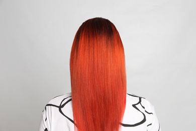 Photo of Woman with bright dyed hair on grey background, back view