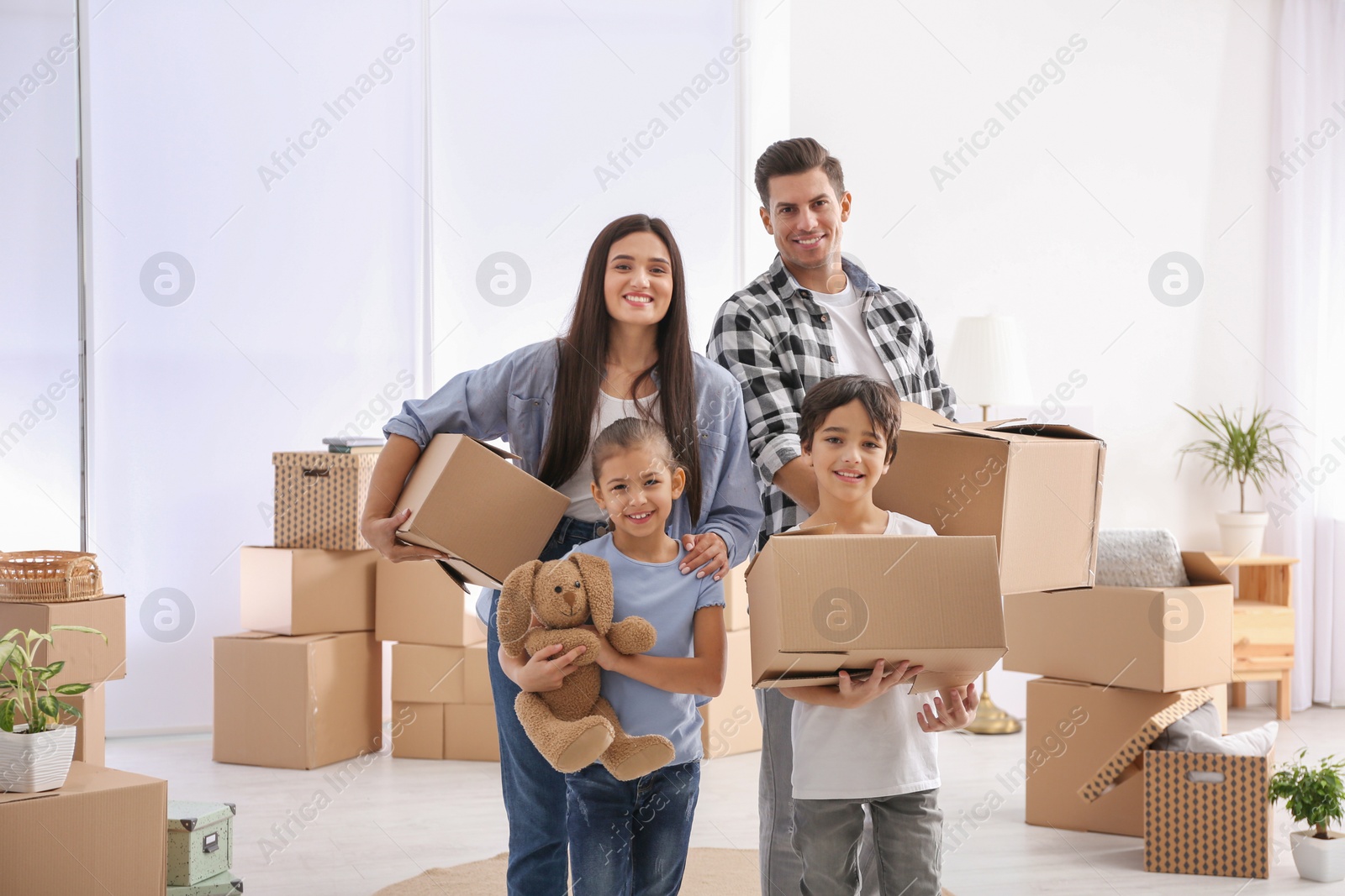 Photo of Happy family in room with cardboard boxes on moving day