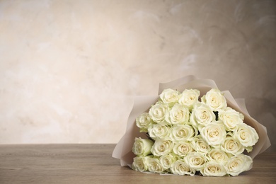 Luxury bouquet of fresh roses on wooden table, space for text