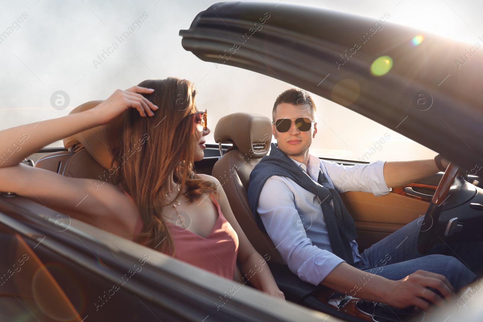 Photo of Stylish couple driving luxury convertible car outdoors