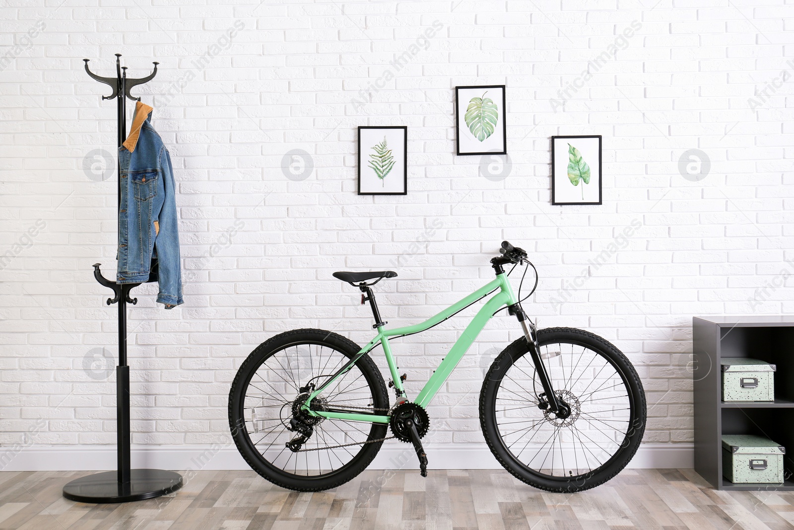 Photo of Modern green bicycle near white brick wall in stylish room interior