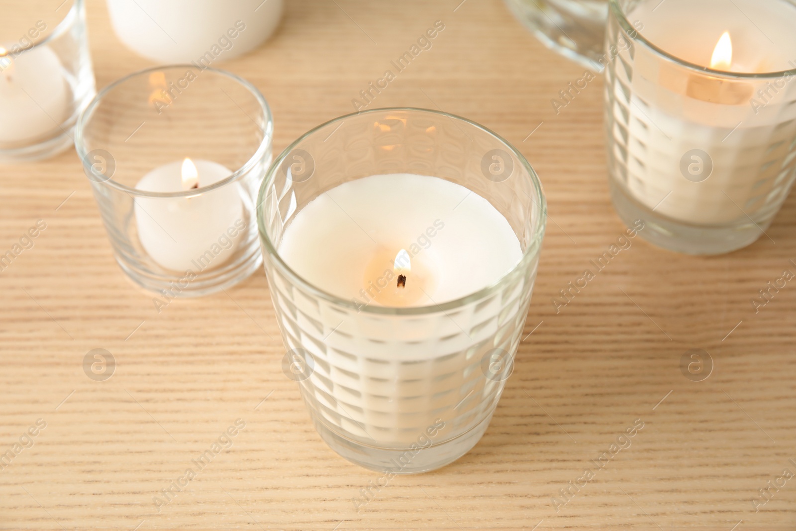 Photo of Burning aromatic candles on wooden table. Interior decor