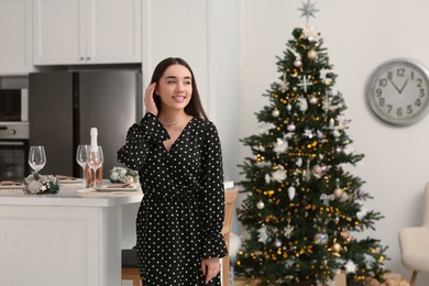 Happy woman near table served for Christmas in kitchen