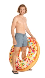 Attractive young man in swimwear with doughnut inflatable ring on white background