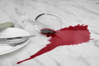 Photo of Overturned glass and spilled red wine on white marble table