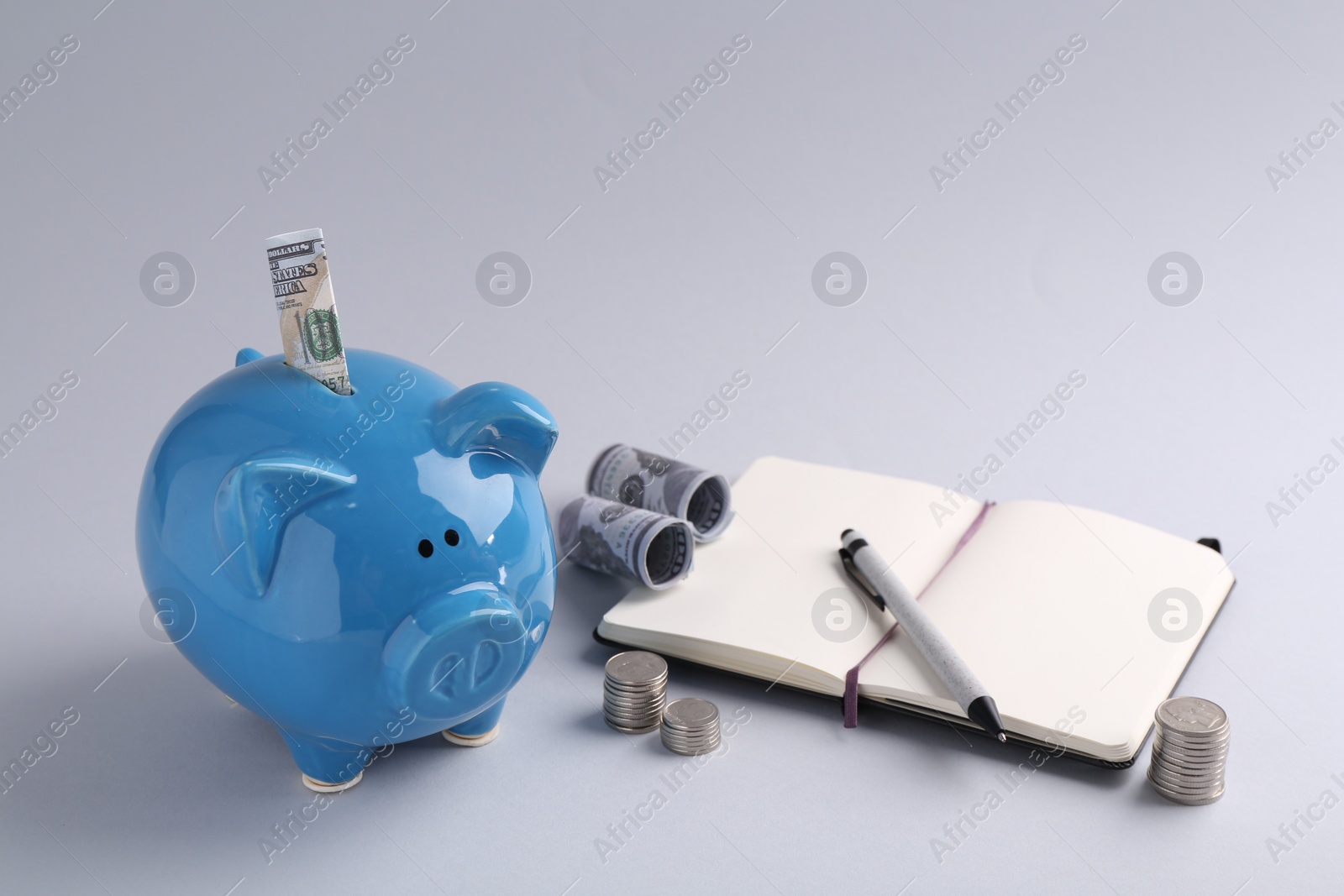 Photo of Financial savings. Piggy bank, dollar banknotes, coins and stationery on grey background