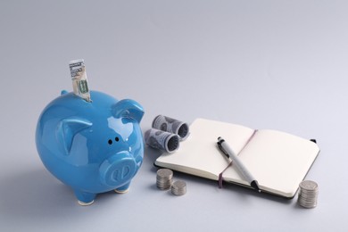Photo of Financial savings. Piggy bank, dollar banknotes, coins and stationery on grey background