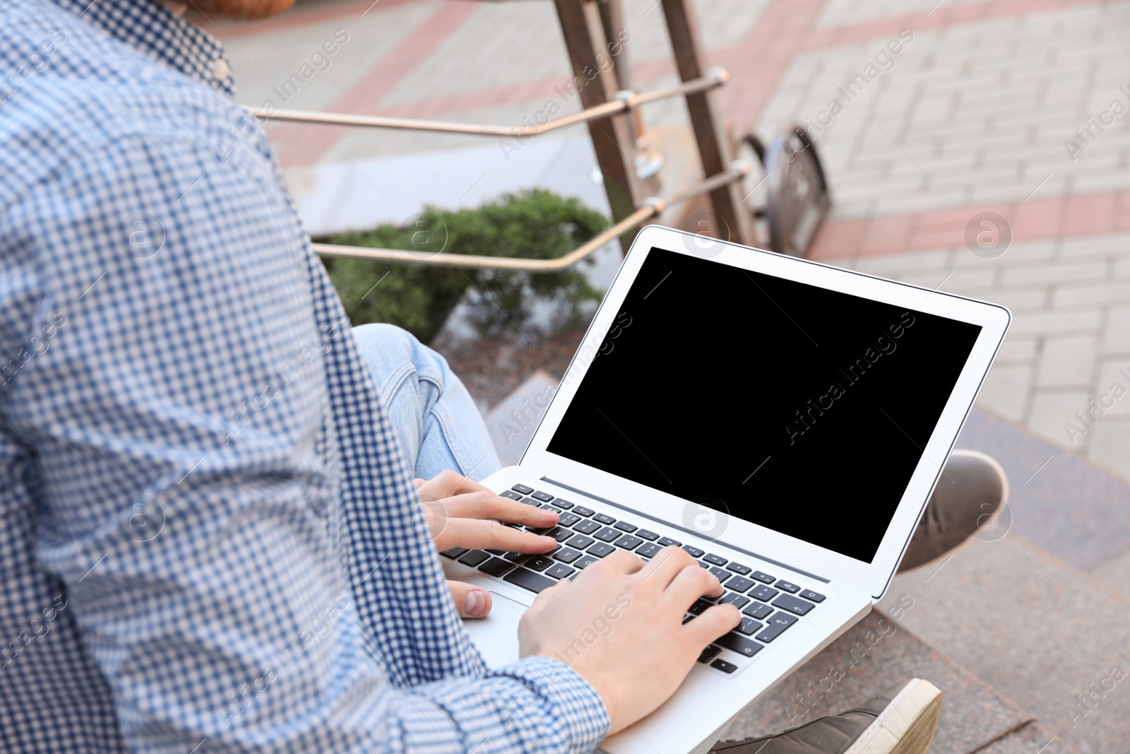 Image of Young man working on laptop outdoors, closeup