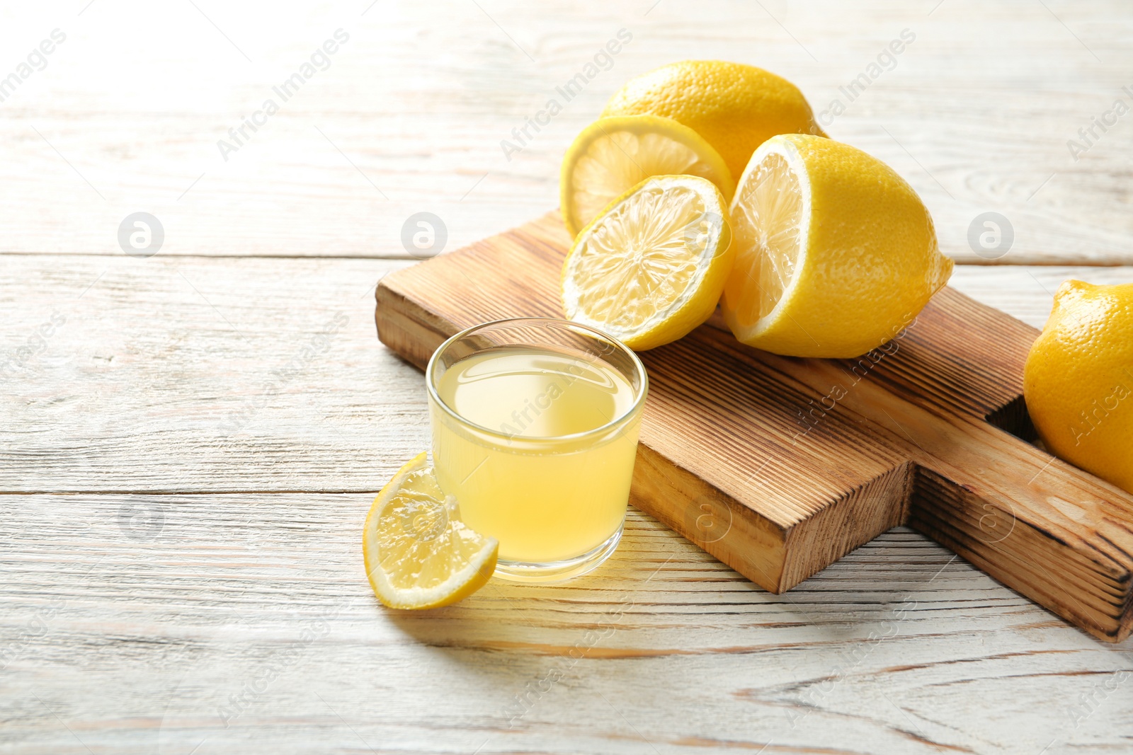 Photo of Glass with fresh lemon juice and fruits on table