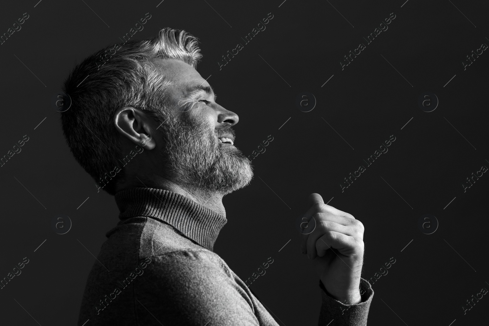 Photo of Portrait of smiling man on dark background. Black and white effect