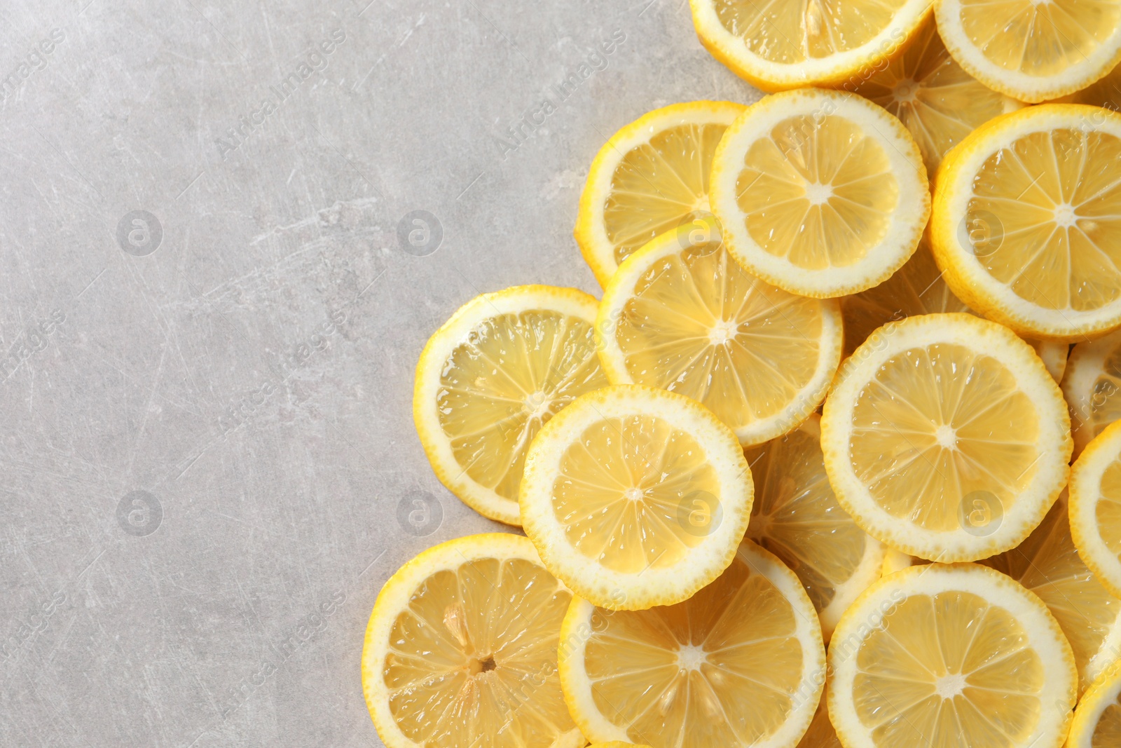 Photo of Slices of fresh lemons on grey table, top view. Space for text