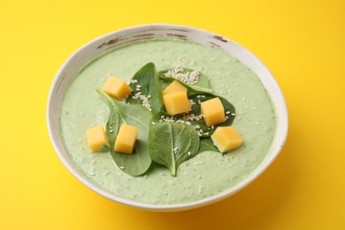 Photo of Delicious spinach cream soup with cheese in bowl on yellow background