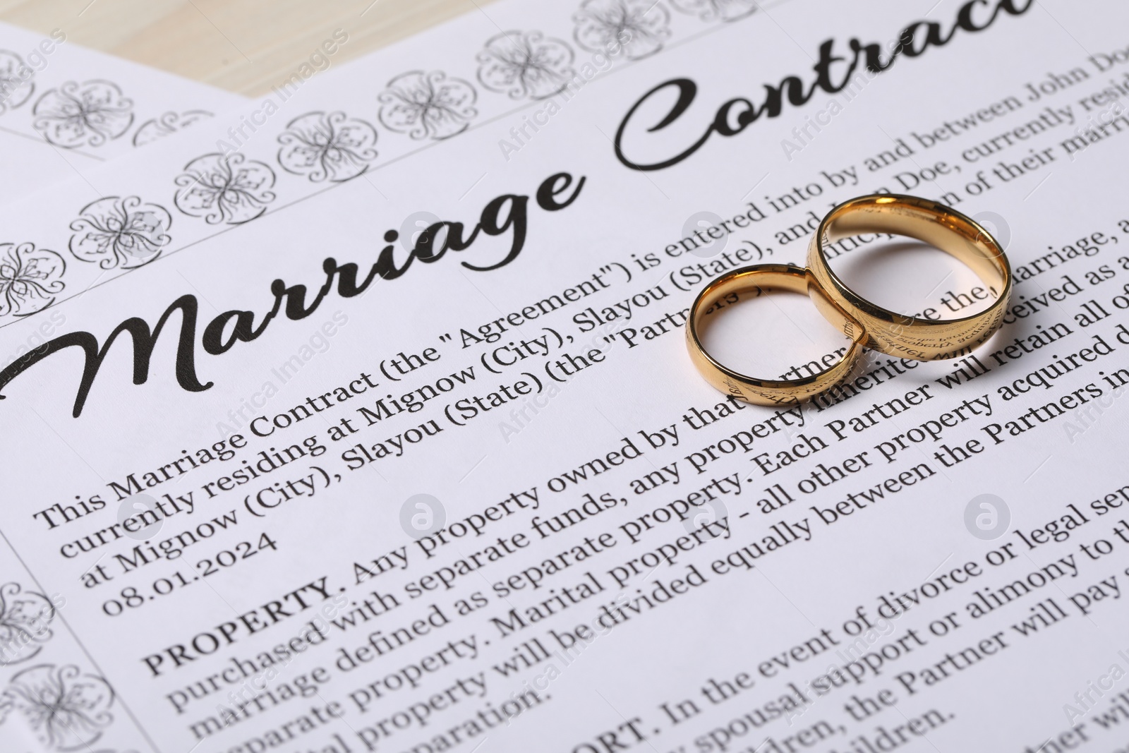 Photo of Marriage contracts and gold rings on light wooden table, closeup