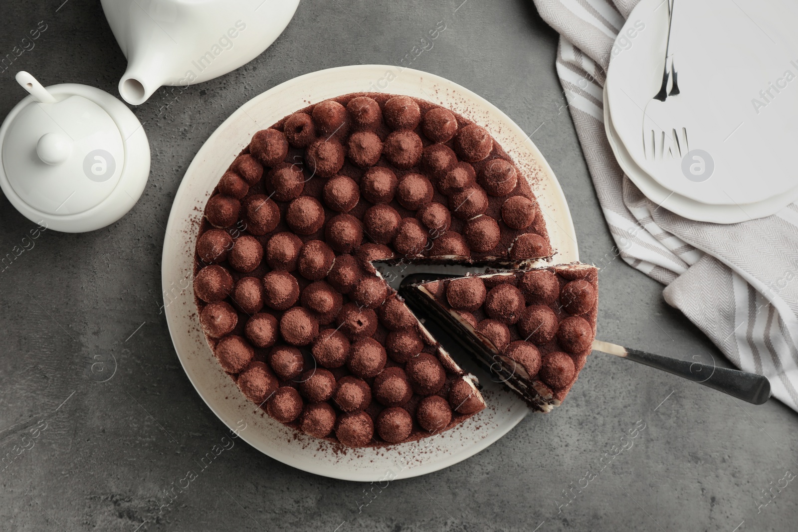 Photo of Delicious tiramisu cake with cocoa powder and server on grey table, flat lay