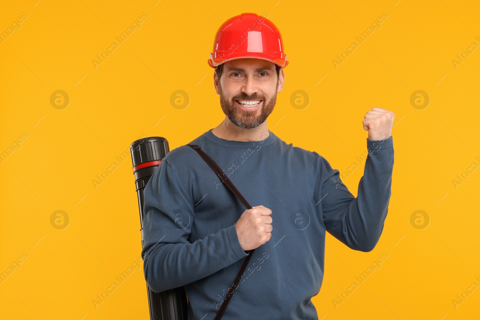 Photo of Architect in hard hat with drawing tube on orange background
