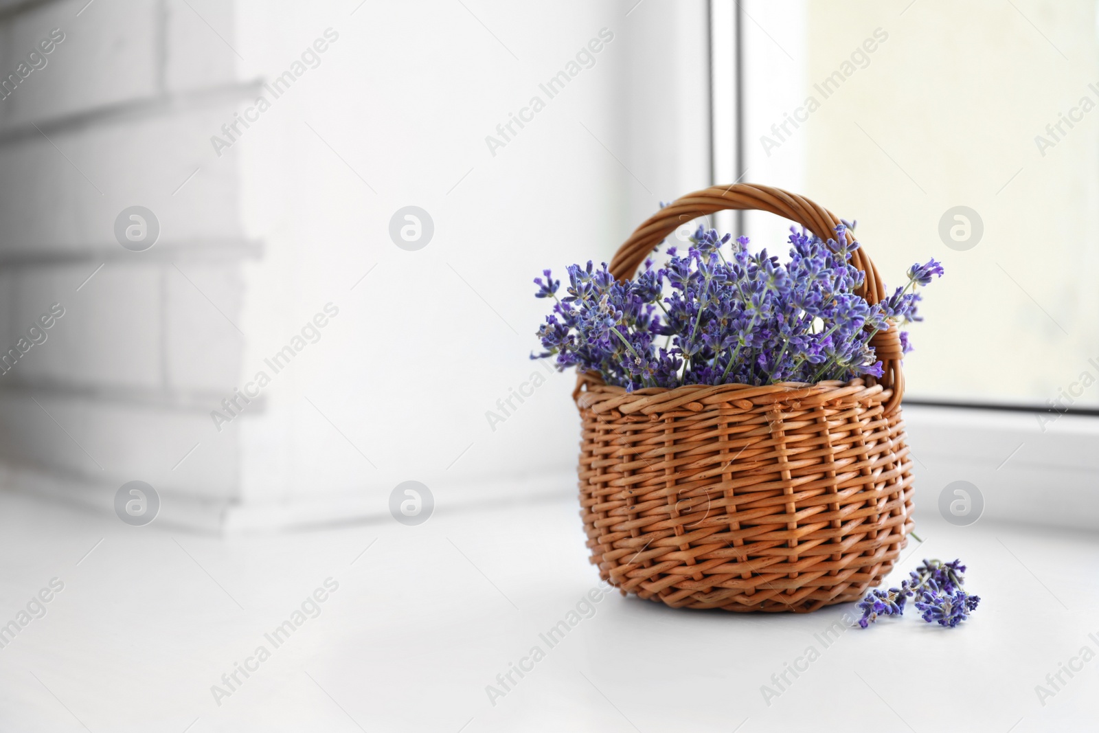 Photo of Fresh lavender flowers in basket on window sill, space for text