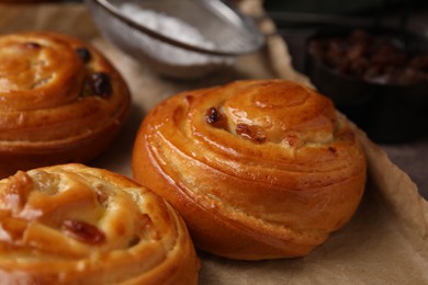 Photo of Delicious rolls with raisins on table, closeup. Sweet buns