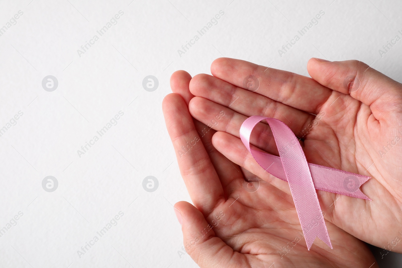 Photo of Woman holding pink ribbon on white background, top view with space for text. Breast cancer awareness concept