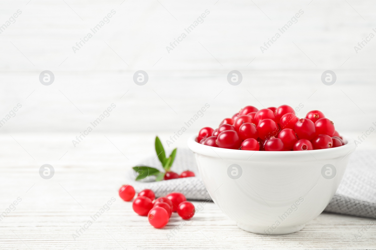 Photo of Tasty ripe cranberries on white wooden table. Space for text