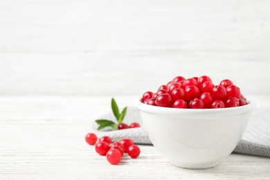 Photo of Tasty ripe cranberries on white wooden table. Space for text