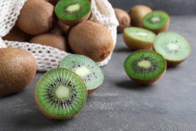 Photo of Cut and whole fresh ripe kiwis on grey table, closeup