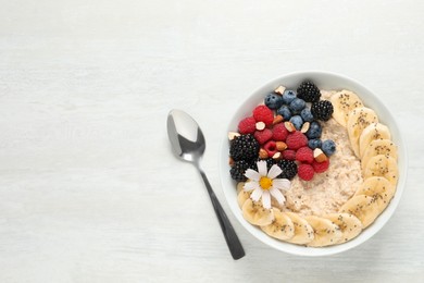 Photo of Tasty oatmeal porridge with berries, banana and chia seeds served on light wooden table, flat lay. Space for text