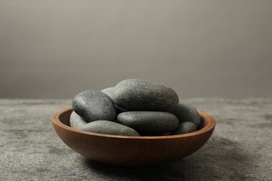 Photo of Bowl with spa stones on grey table, closeup