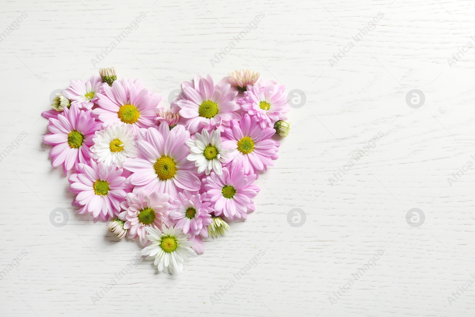 Photo of Heart of beautiful chamomile flowers on wooden background, flat lay with space for text