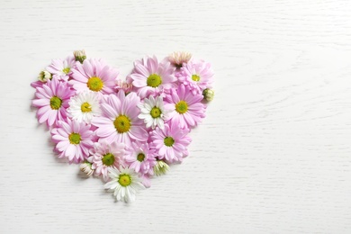 Photo of Heart of beautiful chamomile flowers on wooden background, flat lay with space for text