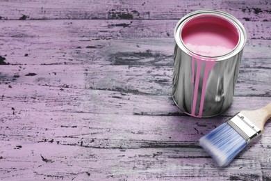 Photo of Can of pink paint and brush on rustic wooden table, space for text