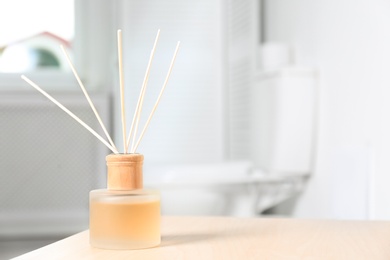 Photo of Reed air freshener with essential oils on table in bathroom. Space for text