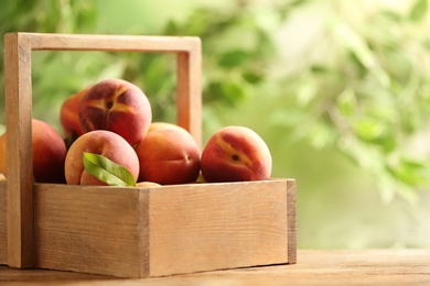 Photo of Fresh sweet peaches in wooden crate on table outdoors
