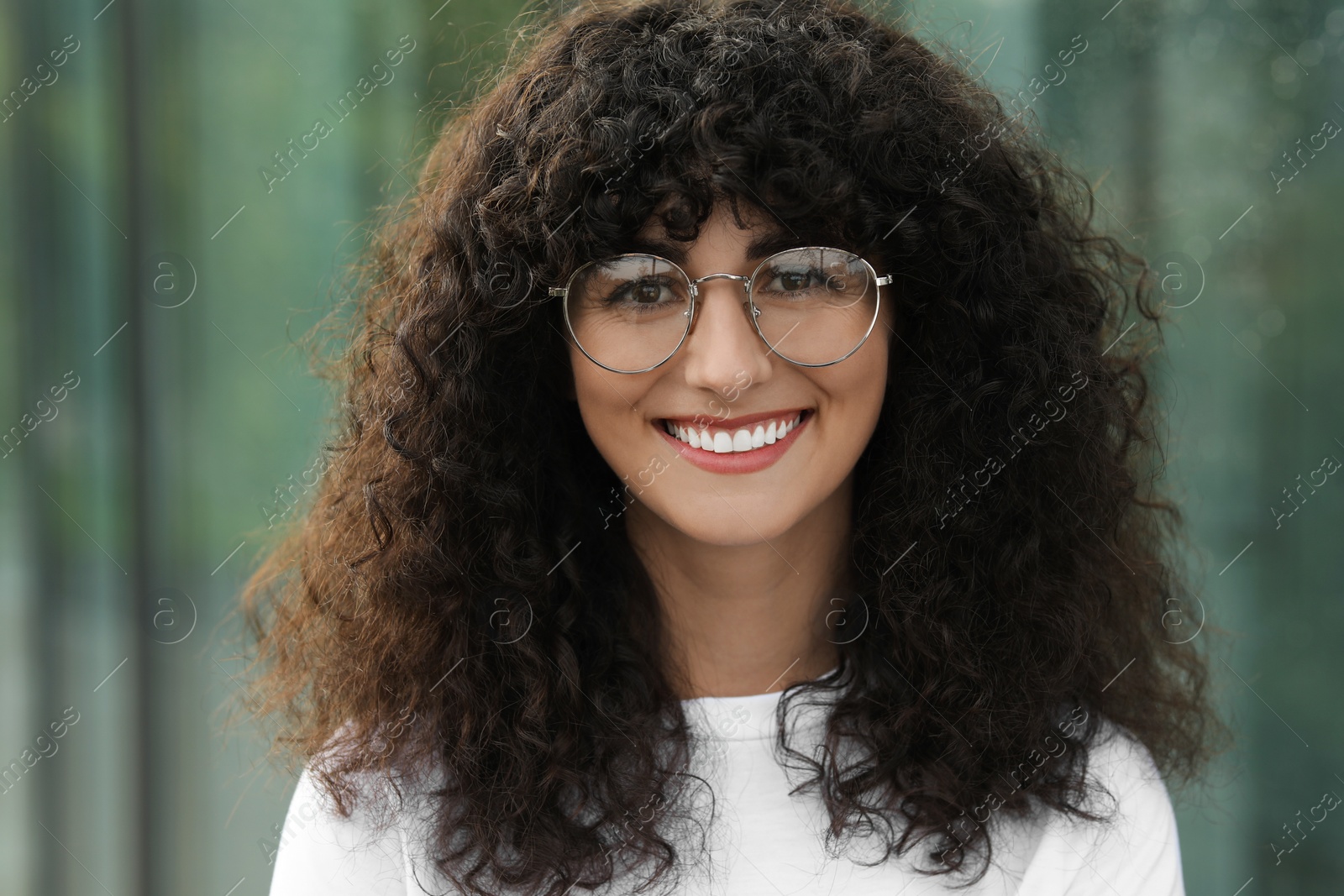 Photo of Portrait of beautiful woman in glasses on blurred background. Attractive lady smiling and looking into camera