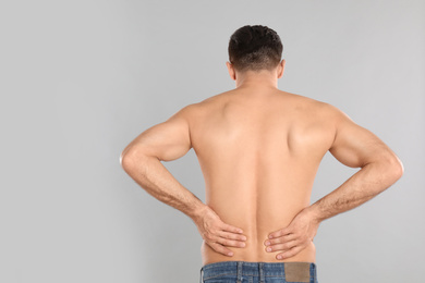 Photo of Man suffering from lower back pain on light grey background. Visiting orthopedist