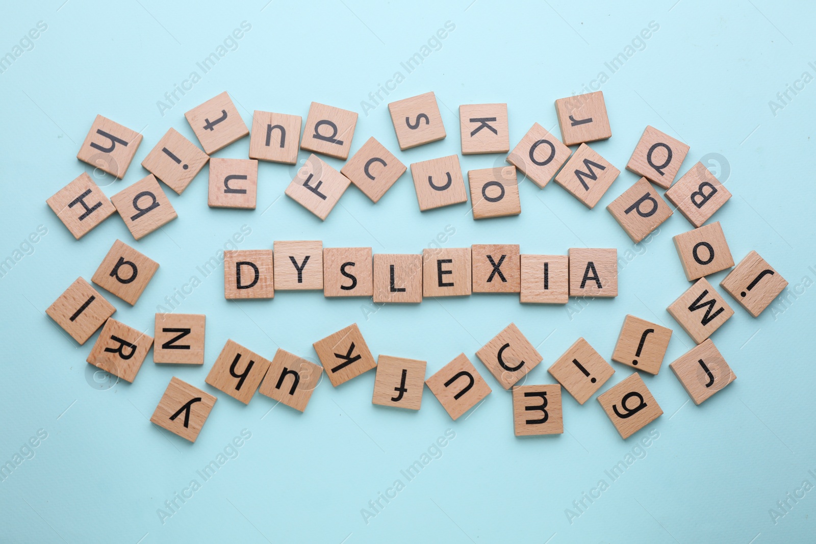 Photo of Wooden tiles with word Dyslexia on light blue background, flat lay