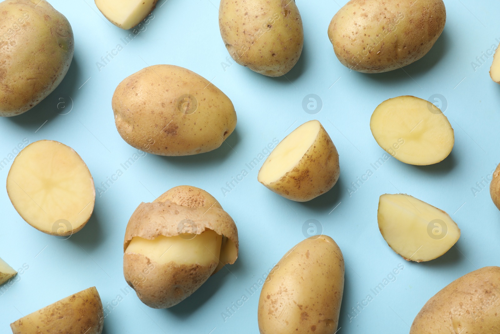 Photo of Fresh raw potatoes on light blue background, flat lay