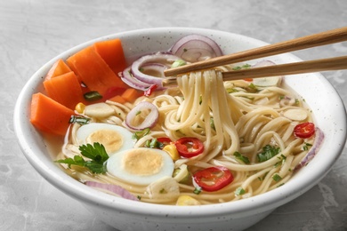 Photo of Eating noodle dish with chopsticks on table, closeup