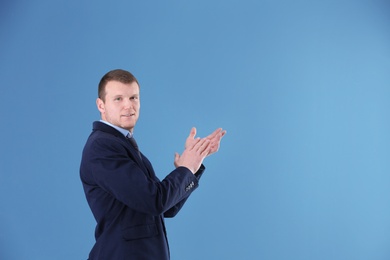 Business trainer applauding on color background