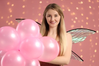 Photo of Beautiful girl in fairy costume with wings and balloons on pink background