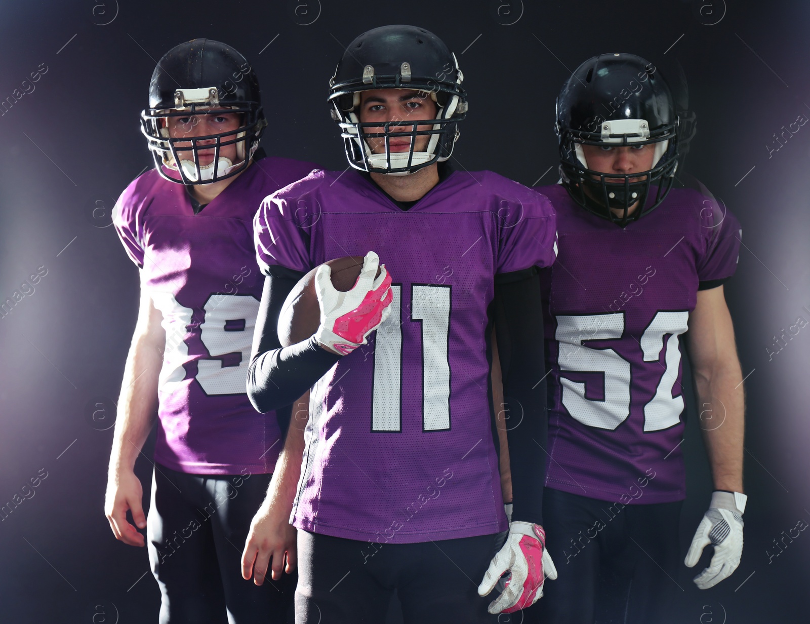 Photo of American football players in uniform on dark background