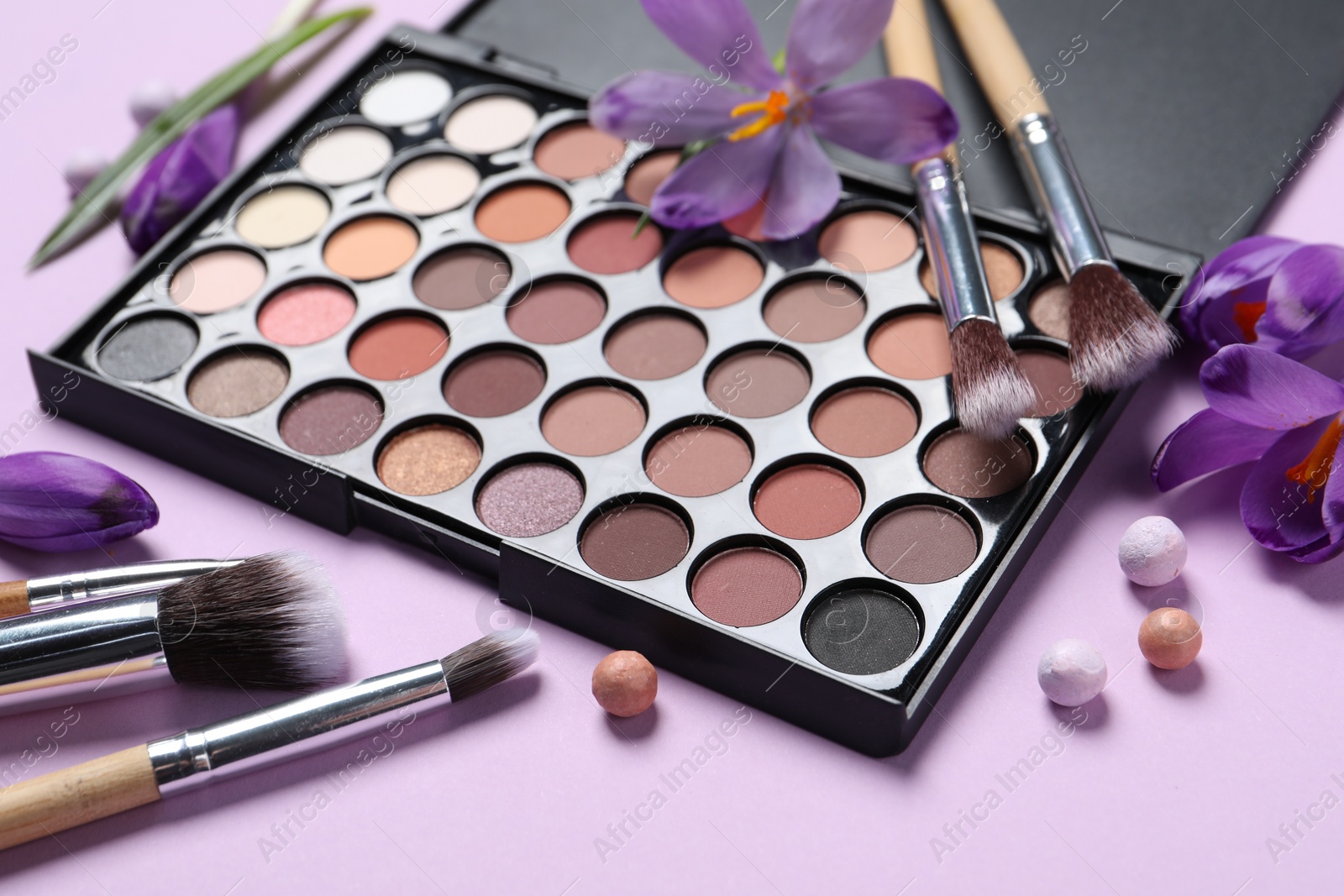 Photo of Composition with eyeshadow palette and beautiful crocuses on lilac background