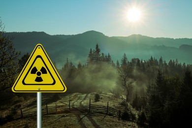 Image of Radioactive pollution. Yellow warning sign with hazard symbol in mountains