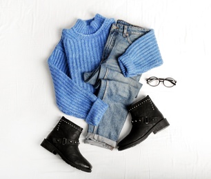 Photo of Flat lay composition with jeans, sweater and shoes on white fabric