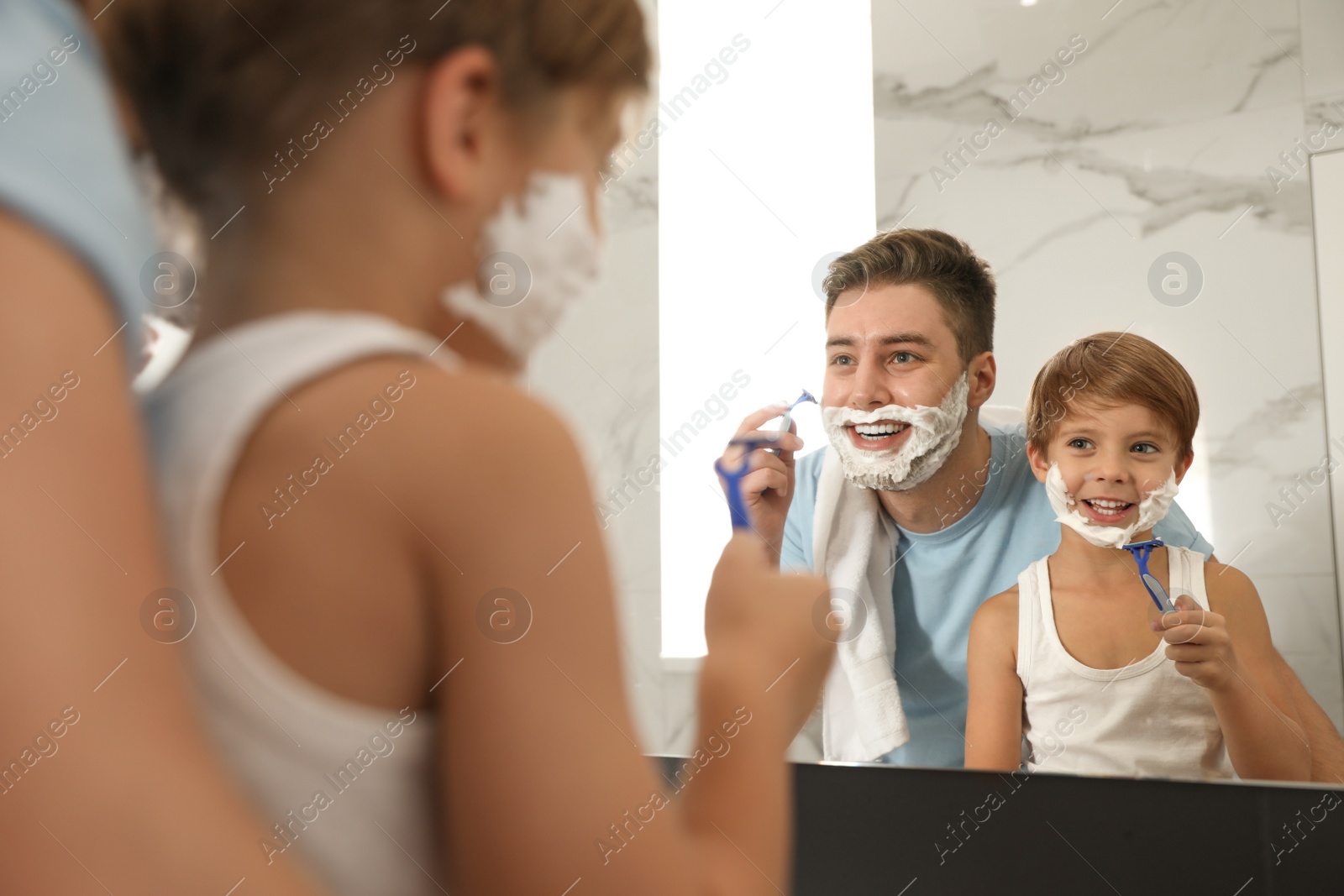 Photo of Dad shaving and son imitating him in bathroom