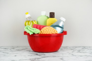 Photo of Red basin with cleaning products on marble table