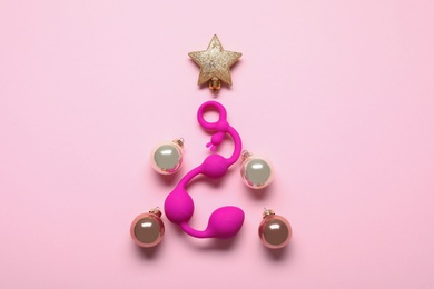 Photo of Christmas tree made with decorative balls, star and sex toy on pink background, flat lay