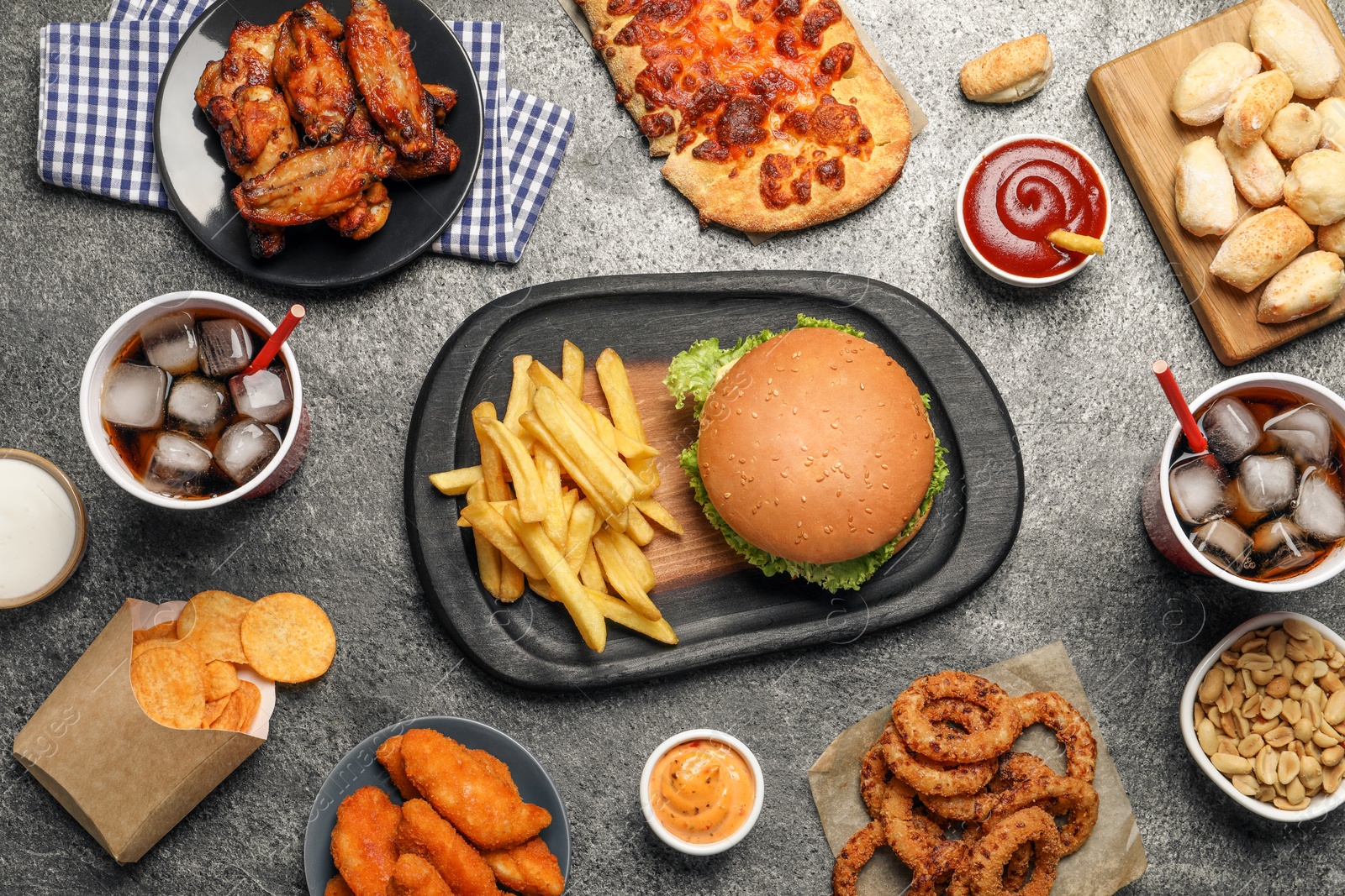 Photo of French fries, burger and other fast food on gray textured table, flat lay