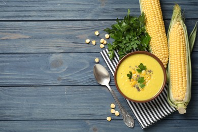 Photo of Delicious creamy corn soup served on blue wooden table, flat lay. Space for text