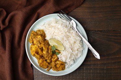 Photo of Delicious chicken curry with rice on wooden table, top view