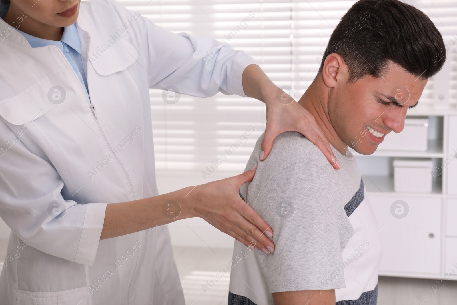 Photo of Doctor examining man with shoulder pain in hospital